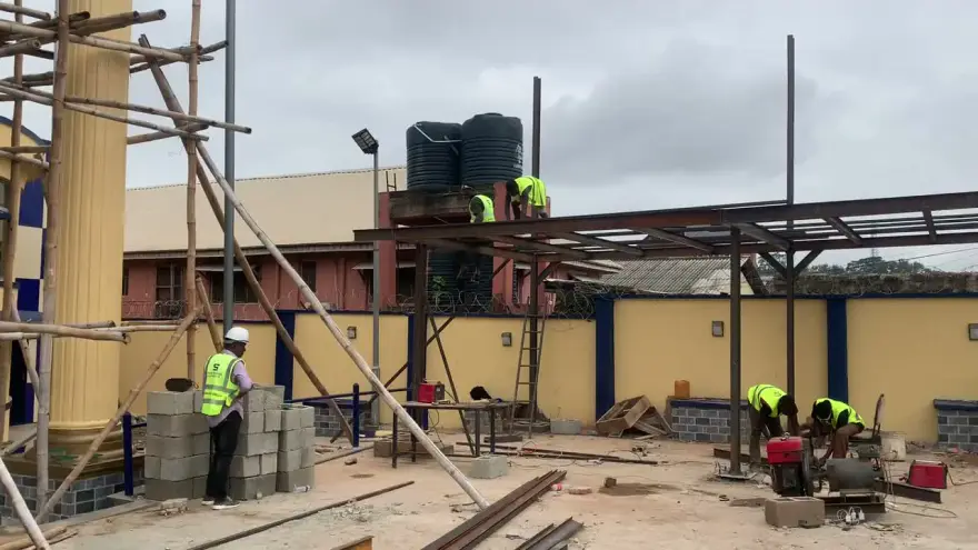 Scaffolding, water tanks, and crew on an active steel canopy build